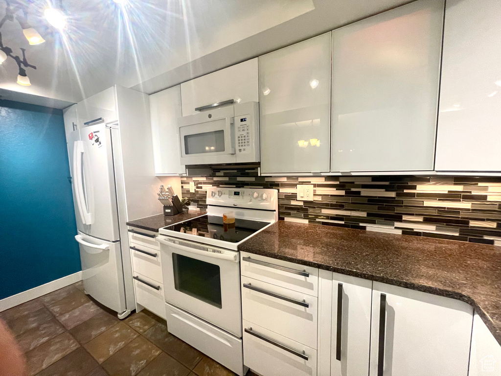 Kitchen featuring white appliances, white cabinets, decorative backsplash, and modern cabinets