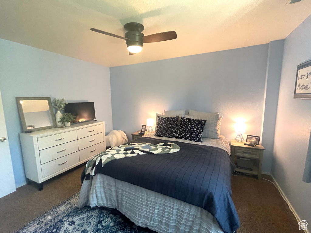 Bedroom with dark carpet and a ceiling fan