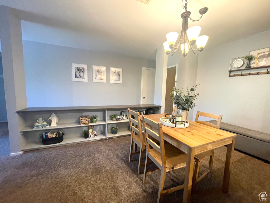 Dining space with dark colored carpet and a chandelier