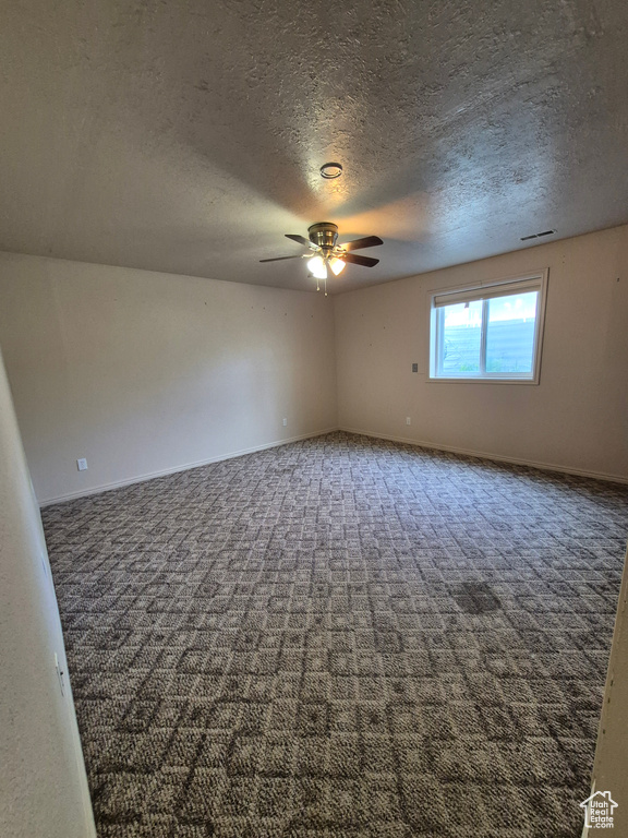 Carpeted spare room featuring ceiling fan and a textured ceiling