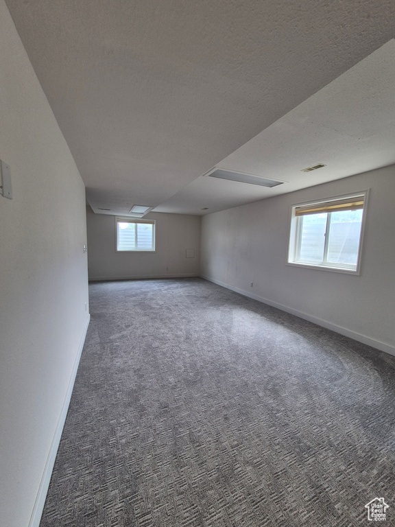 Carpeted empty room featuring plenty of natural light and a textured ceiling