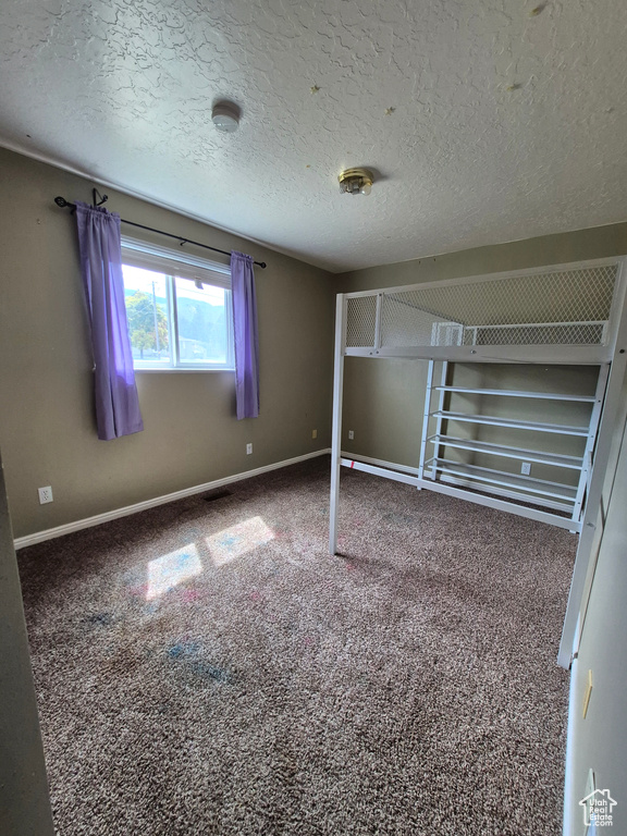 Unfurnished bedroom with carpet floors and a textured ceiling