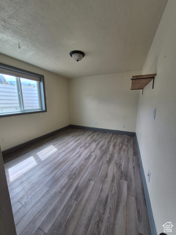 Unfurnished room with wood finished floors and a textured ceiling