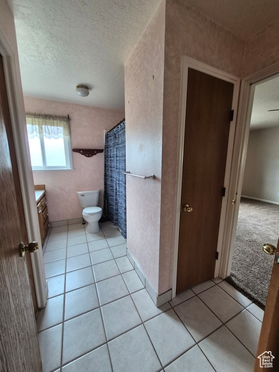 Bathroom with vanity, tile patterned floors, a textured ceiling, and curtained shower