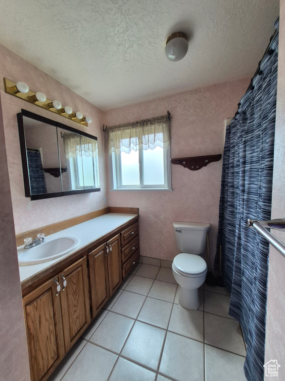 Full bath with vanity, a textured ceiling, and tile patterned floors