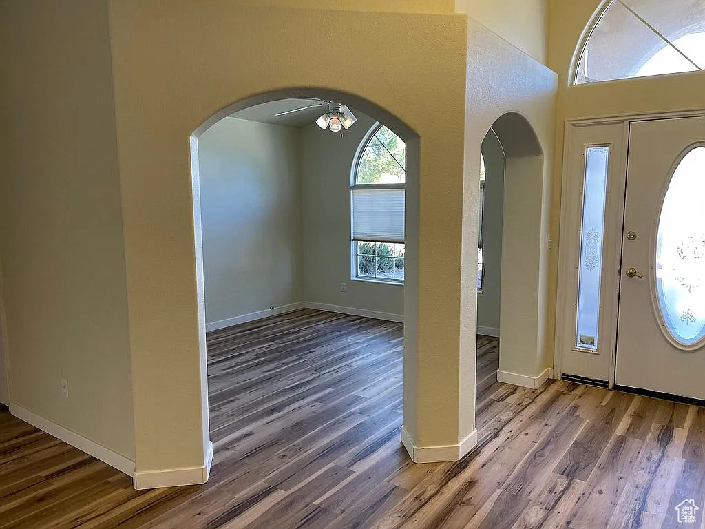 Entrance foyer featuring wood finished floors, arched walkways, and a high ceiling