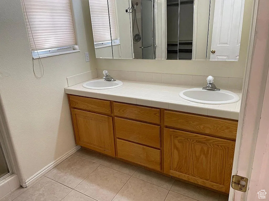 Full bath featuring double vanity, tile patterned flooring, and a shower with shower door