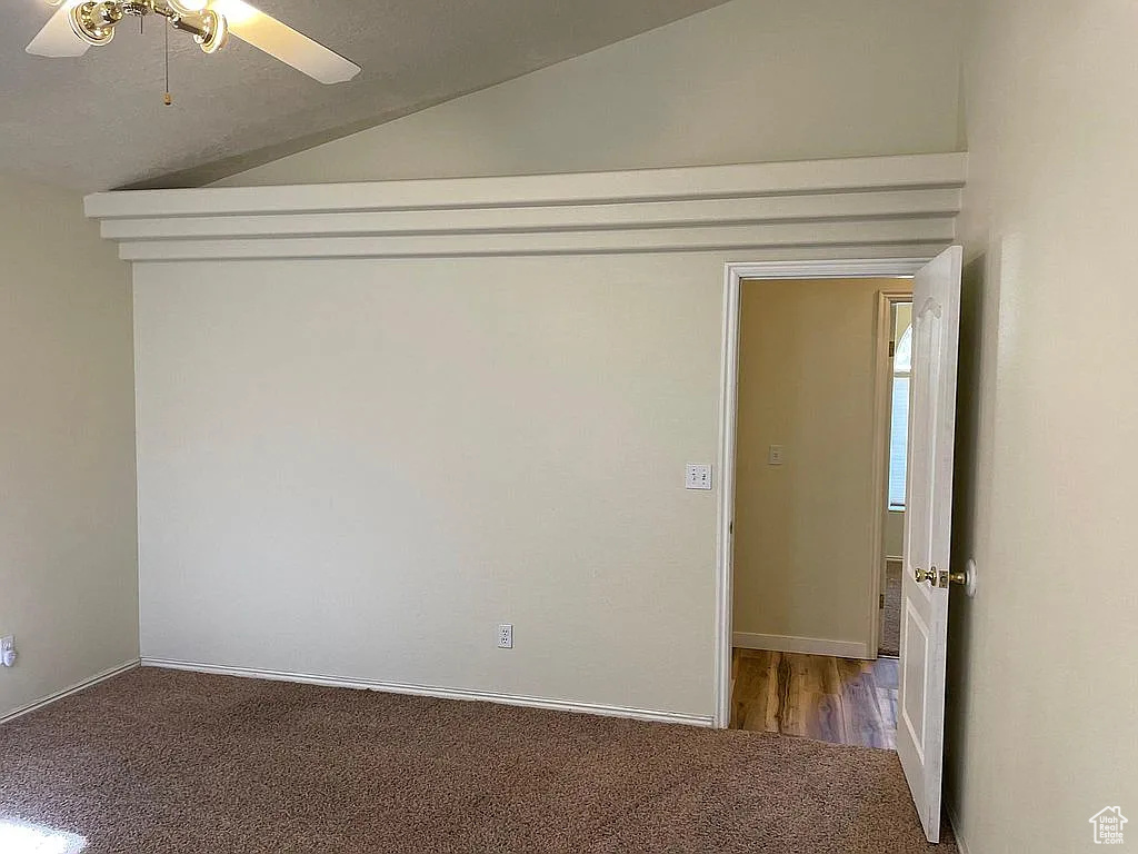 Carpeted spare room featuring lofted ceiling and ceiling fan