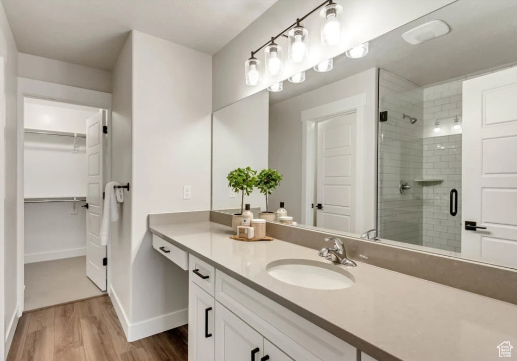 Full bath with a walk in closet, a shower stall, wood finished floors, and vanity