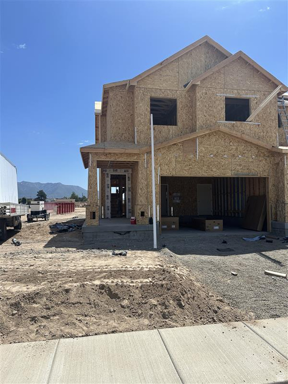 View of front of property featuring a mountain view, dirt driveway, and an attached garage