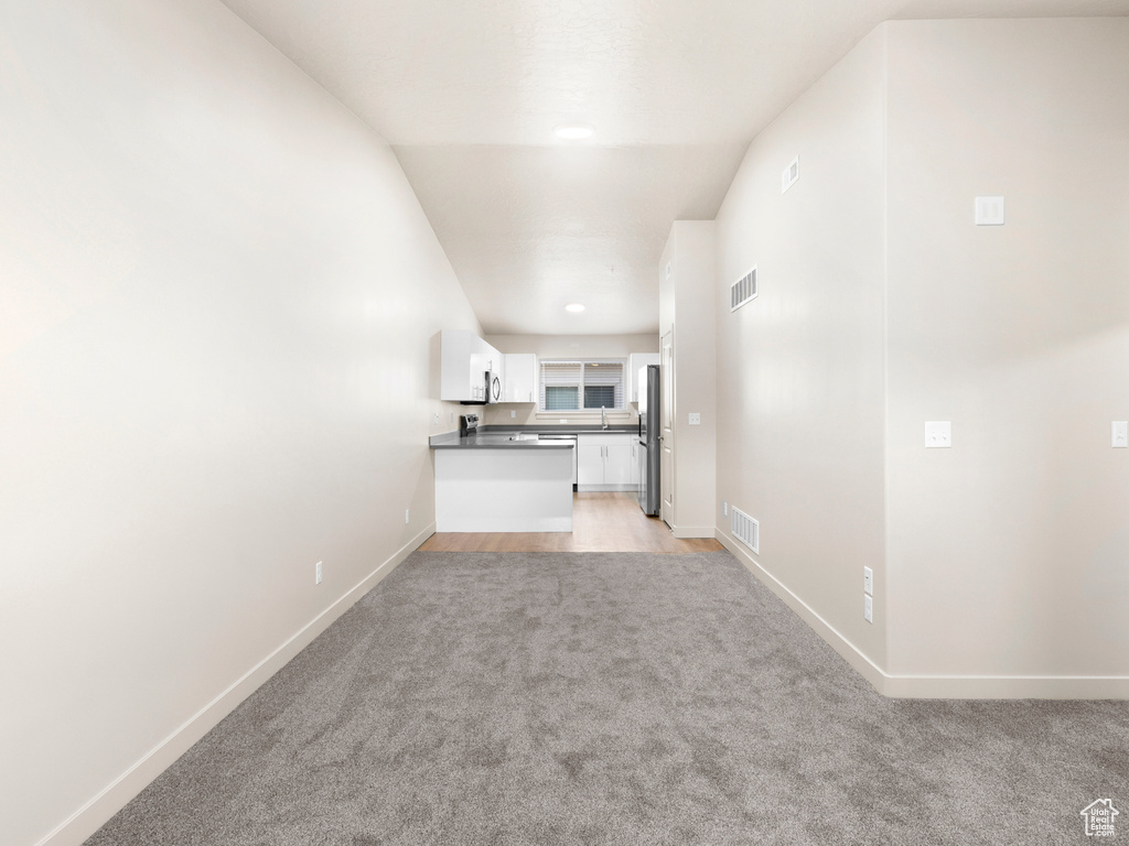 Unfurnished living room with light carpet and baseboards