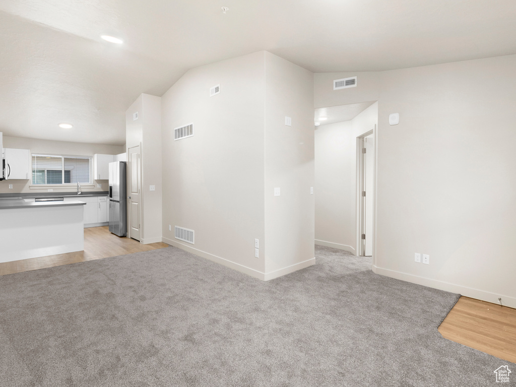 Unfurnished living room with light colored carpet, recessed lighting, and vaulted ceiling