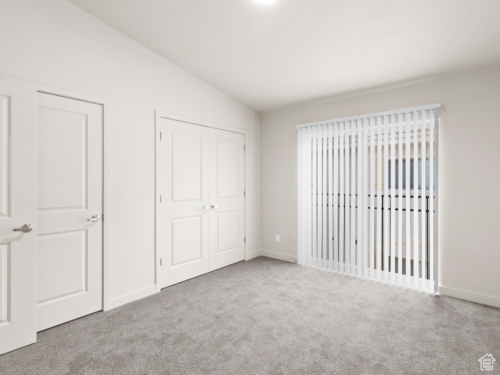 Unfurnished bedroom with vaulted ceiling and carpet floors