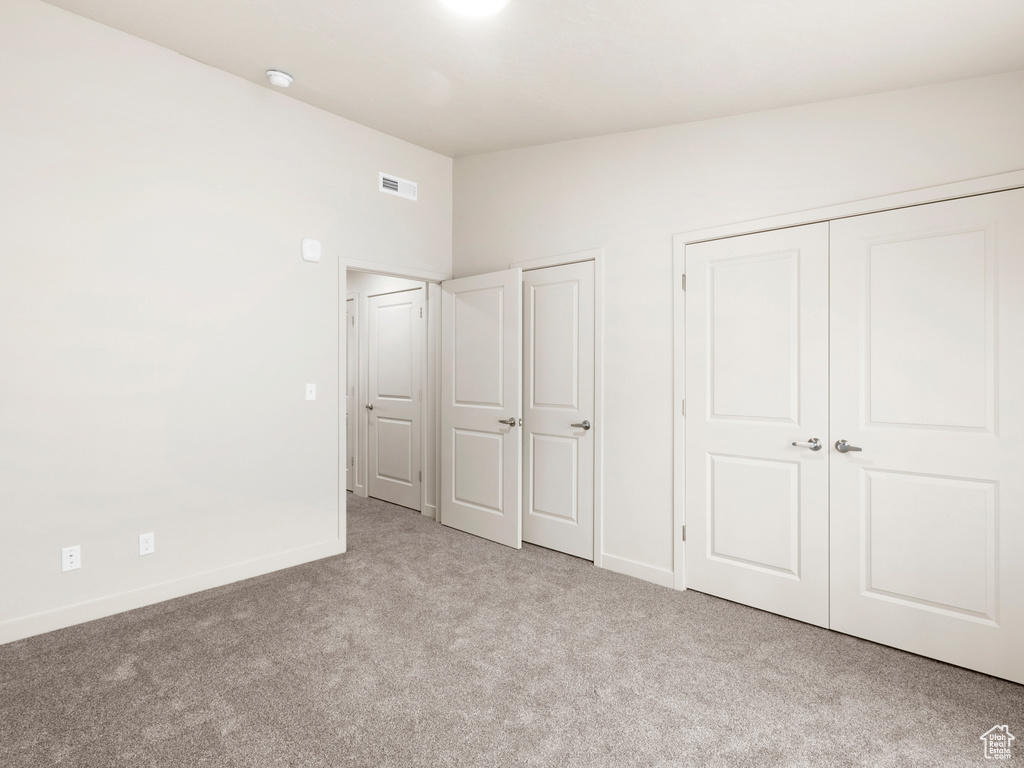 Unfurnished bedroom with carpet flooring, two closets, and vaulted ceiling