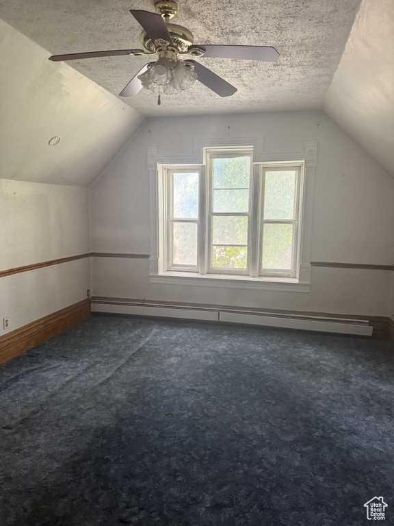 Additional living space featuring lofted ceiling, carpet flooring, a baseboard heating unit, a textured ceiling, and a ceiling fan
