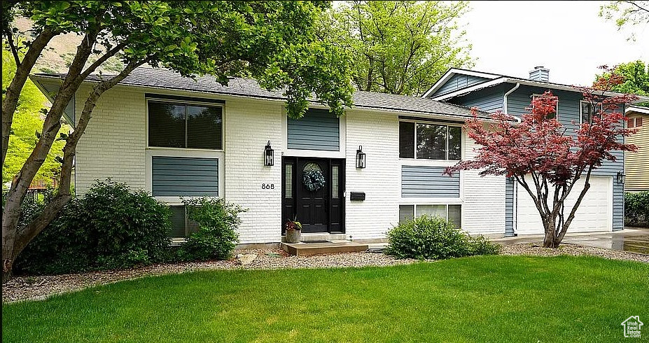 Bi-level home featuring a front yard, an attached garage, and driveway