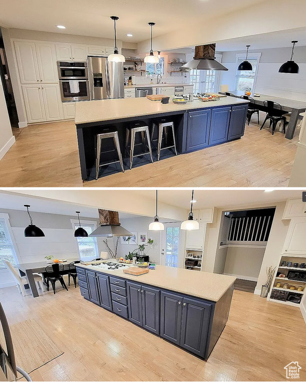 Kitchen with a spacious island, stainless steel appliances, exhaust hood, light wood-type flooring, and recessed lighting