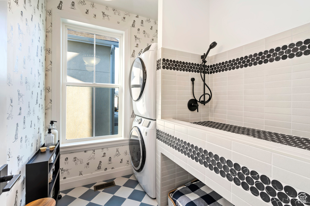 Full bathroom featuring stacked washer and clothes dryer, tiled shower, tile patterned floors, and wallpapered walls