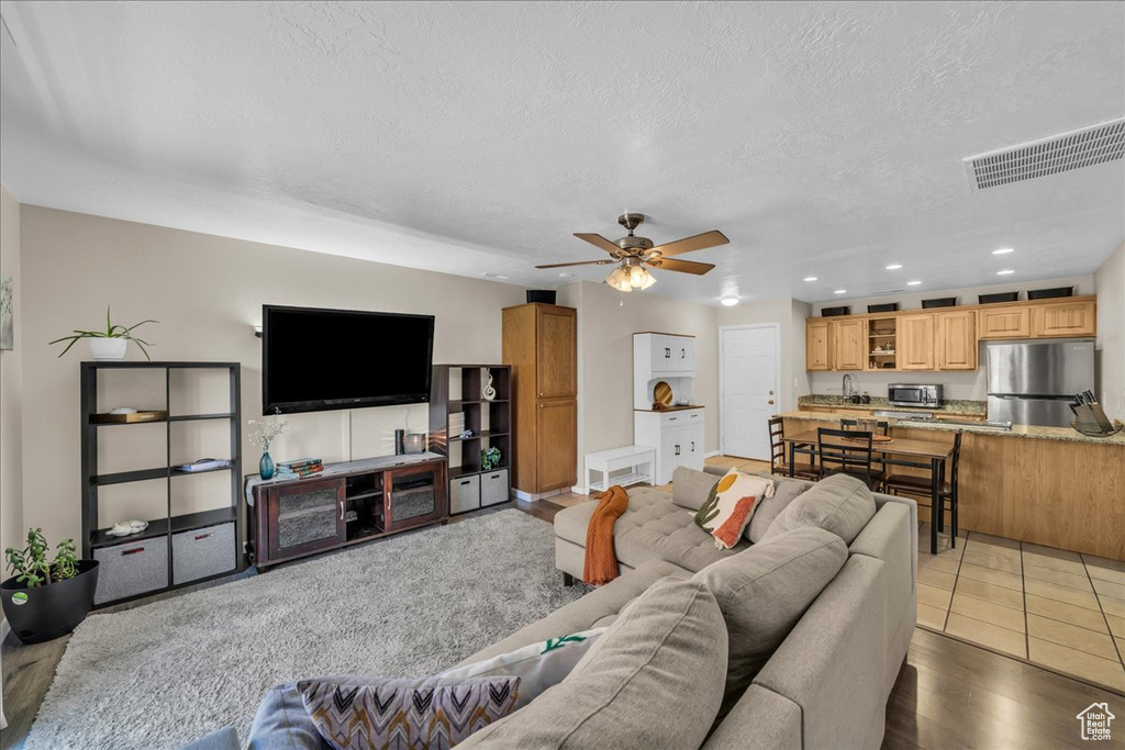 Living area with a textured ceiling, ceiling fan, and recessed lighting