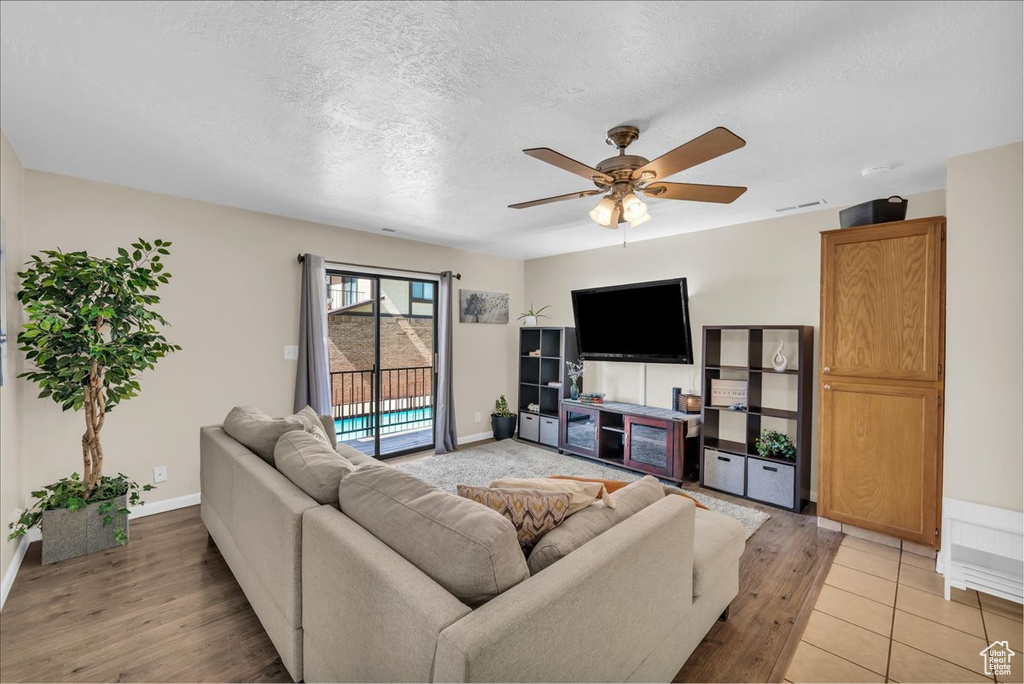 Living room with light wood finished floors, ceiling fan, and a textured ceiling