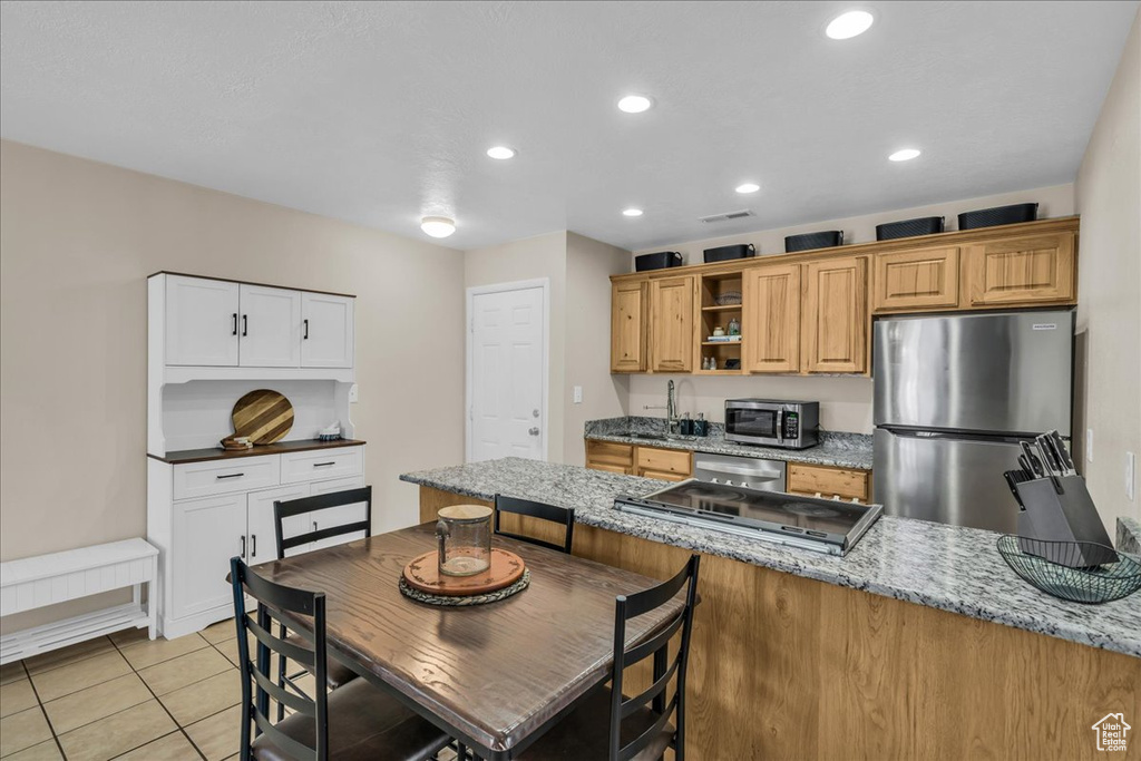 Kitchen with stainless steel appliances, open shelves, light stone counters, a peninsula, and recessed lighting