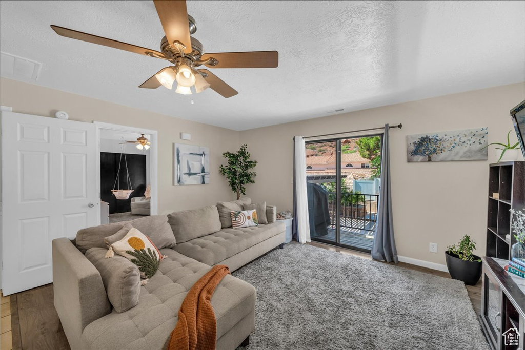 Living room with ceiling fan, wood finished floors, and a textured ceiling