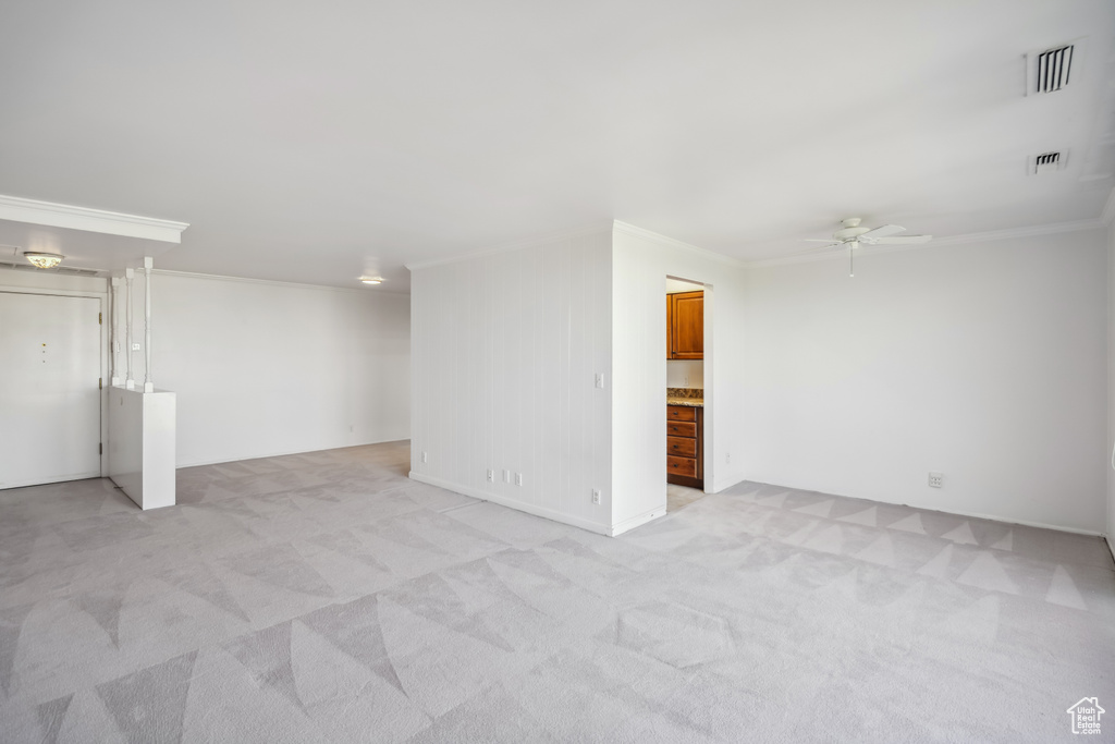Spare room featuring crown molding, a ceiling fan, and light colored carpet