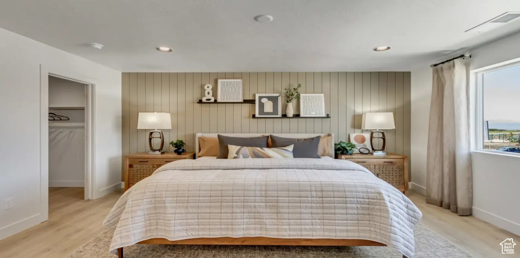 Bedroom with multiple windows, light wood-style floors, a walk in closet, and recessed lighting