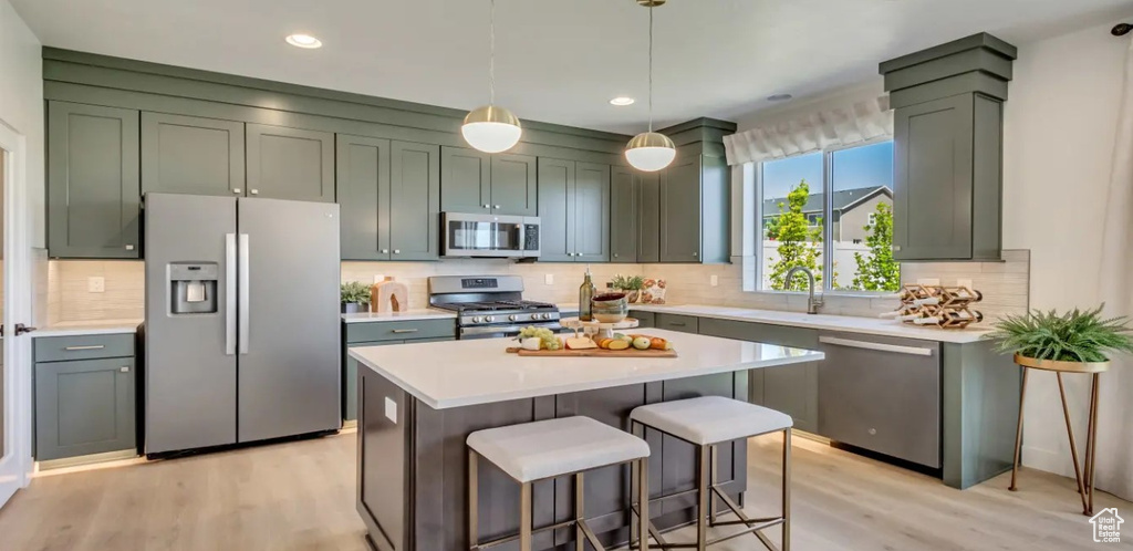 Kitchen featuring appliances with stainless steel finishes, light wood-style floors, light countertops, decorative backsplash, and recessed lighting