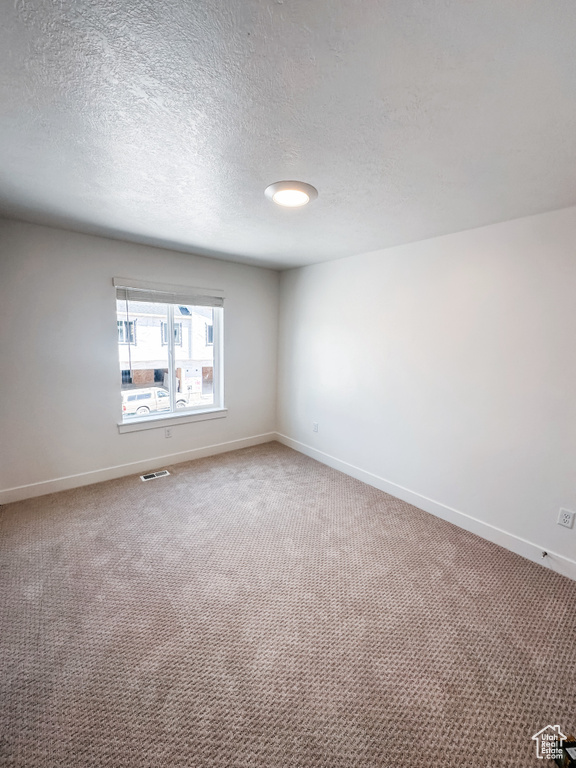 Carpeted empty room featuring a textured ceiling