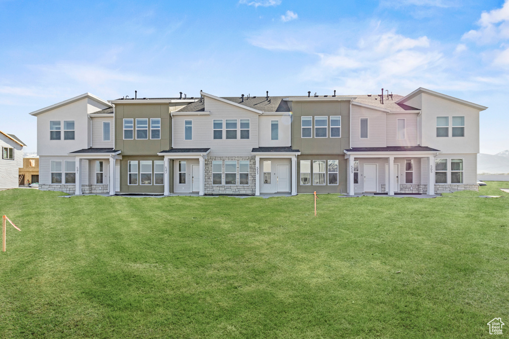 Rear view of property with a yard and stucco siding