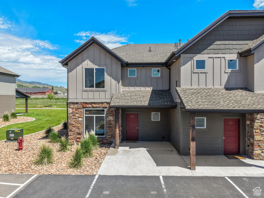 Multi unit property with board and batten siding, roof with shingles, and stone siding