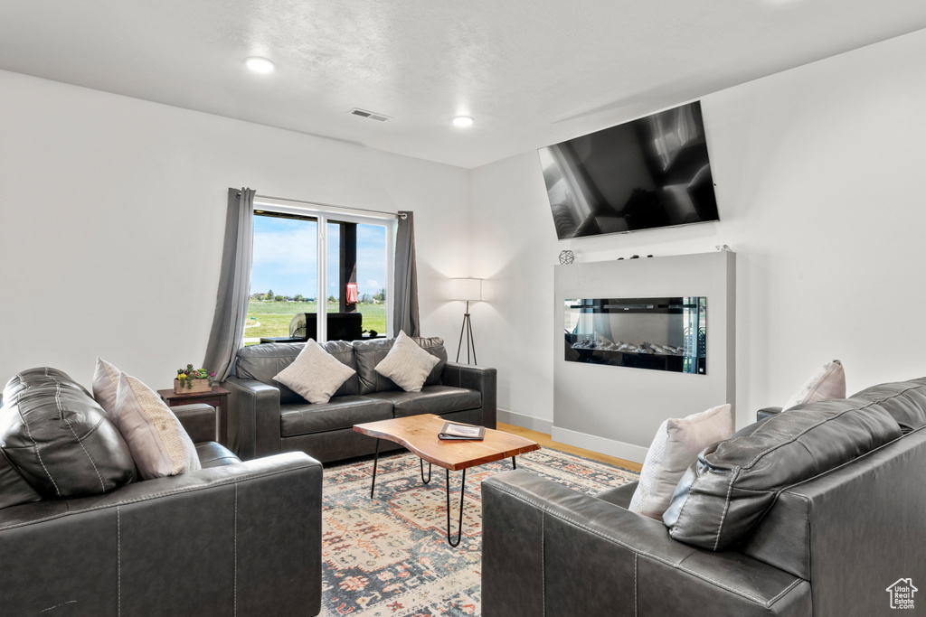 Living area with recessed lighting, wood finished floors, and a glass covered fireplace