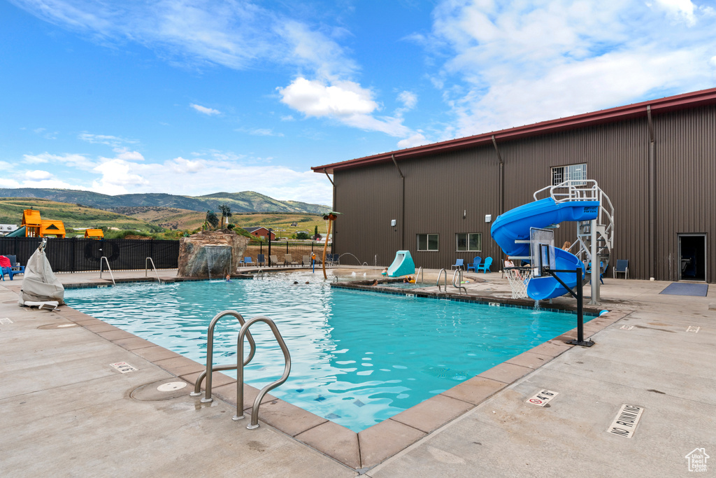 Community pool with a mountain view, a water slide, and a patio area