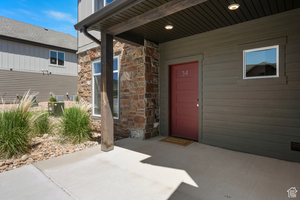 Entrance to property featuring stone siding and a patio