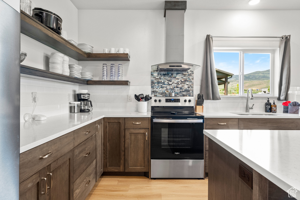 Kitchen with stainless steel electric range oven, extractor fan, open shelves, and decorative backsplash