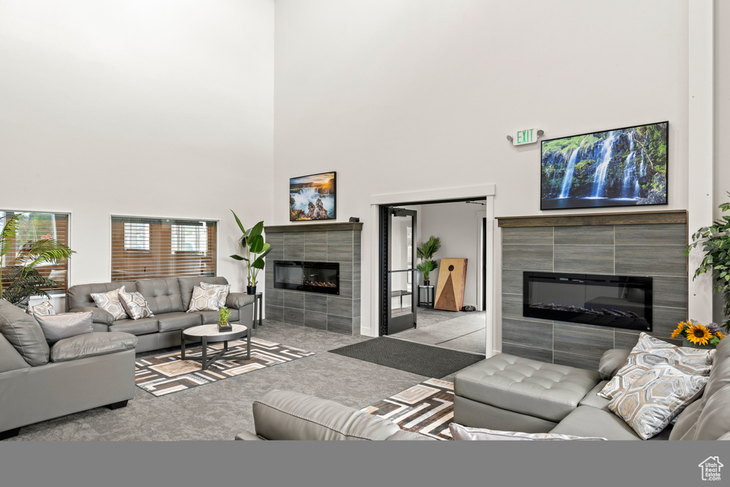 Living area featuring a tiled fireplace, carpet floors, and a towering ceiling
