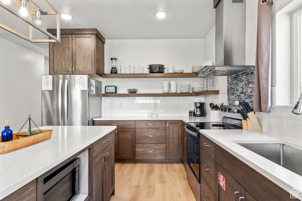 Kitchen with electric range, freestanding refrigerator, island range hood, and open shelves