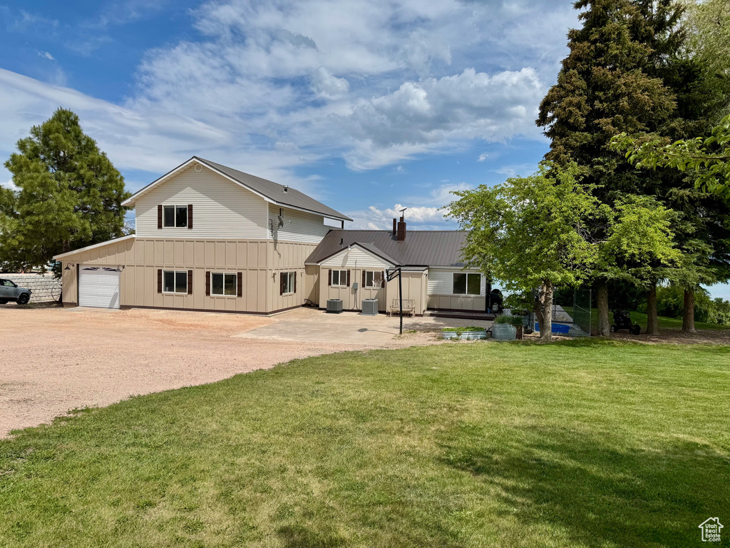 View of front of home with a front yard, board and batten siding, metal roof, a chimney, and driveway
