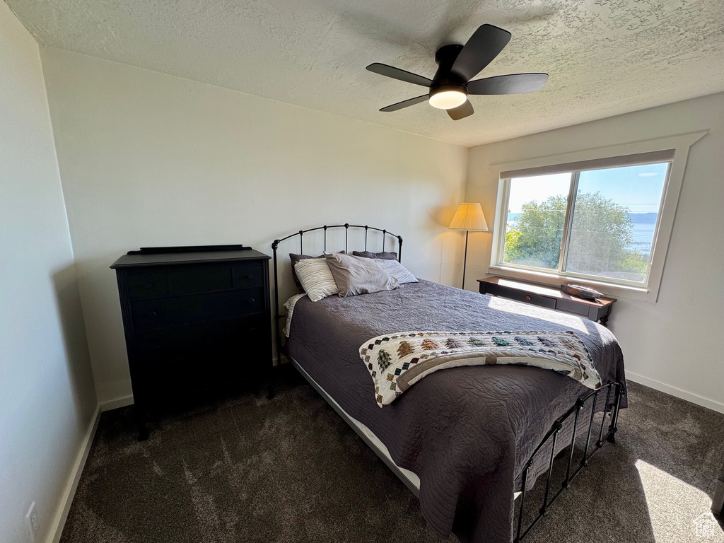 Bedroom with carpet floors, a textured ceiling, and ceiling fan