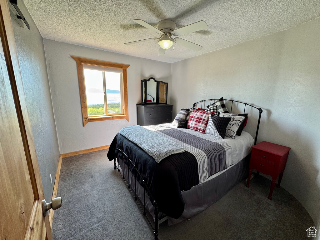 Carpeted bedroom featuring a ceiling fan and a textured ceiling