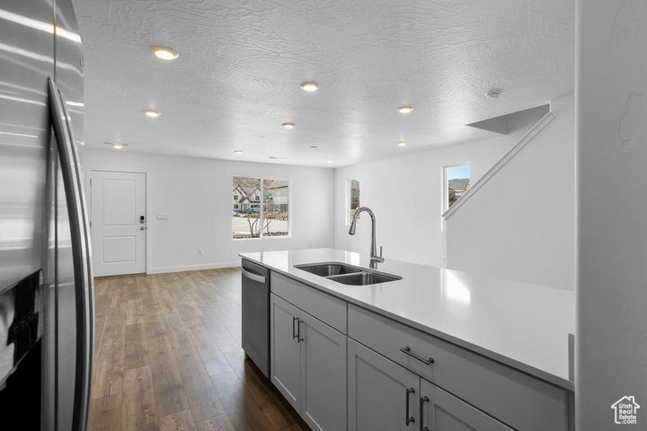 Kitchen with appliances with stainless steel finishes, dark wood-type flooring, light countertops, a textured ceiling, and recessed lighting