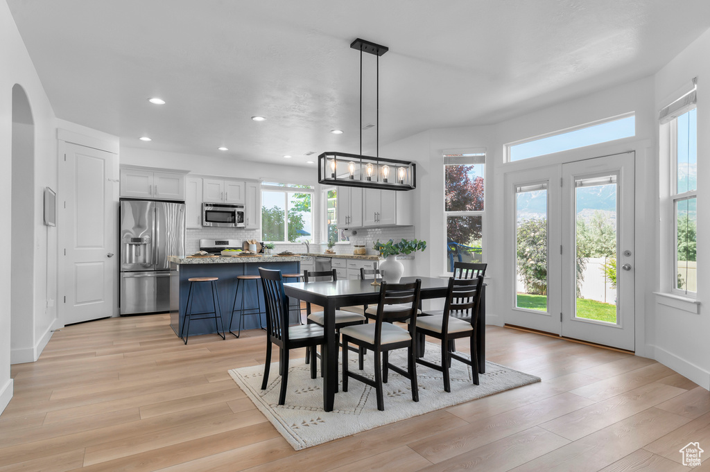 Dining area with recessed lighting, light wood finished floors, and arched walkways