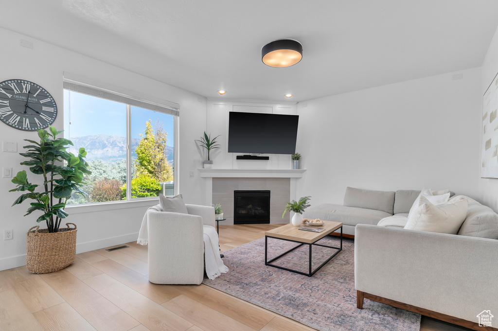 Living room featuring wood finished floors, a tiled fireplace, and recessed lighting