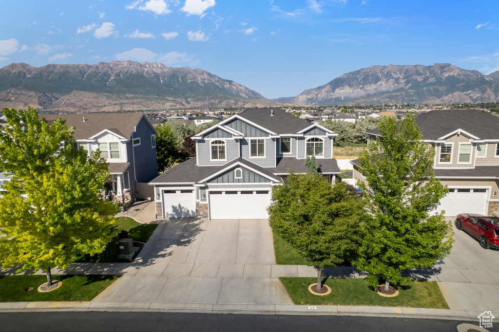 View of front of property featuring board and batten siding, driveway, a mountain view, and a residential view