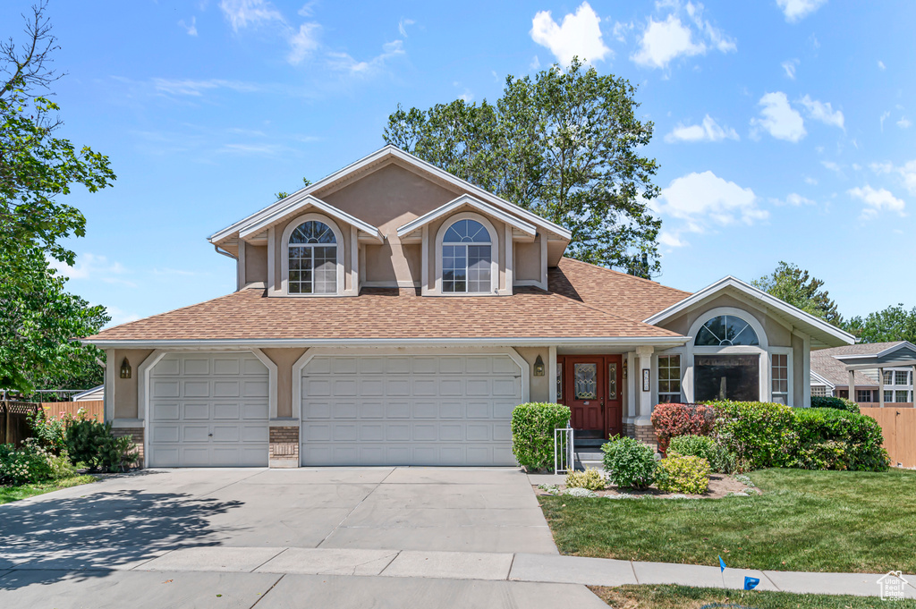 View of front facade with driveway, a shingled roof, and stucco siding