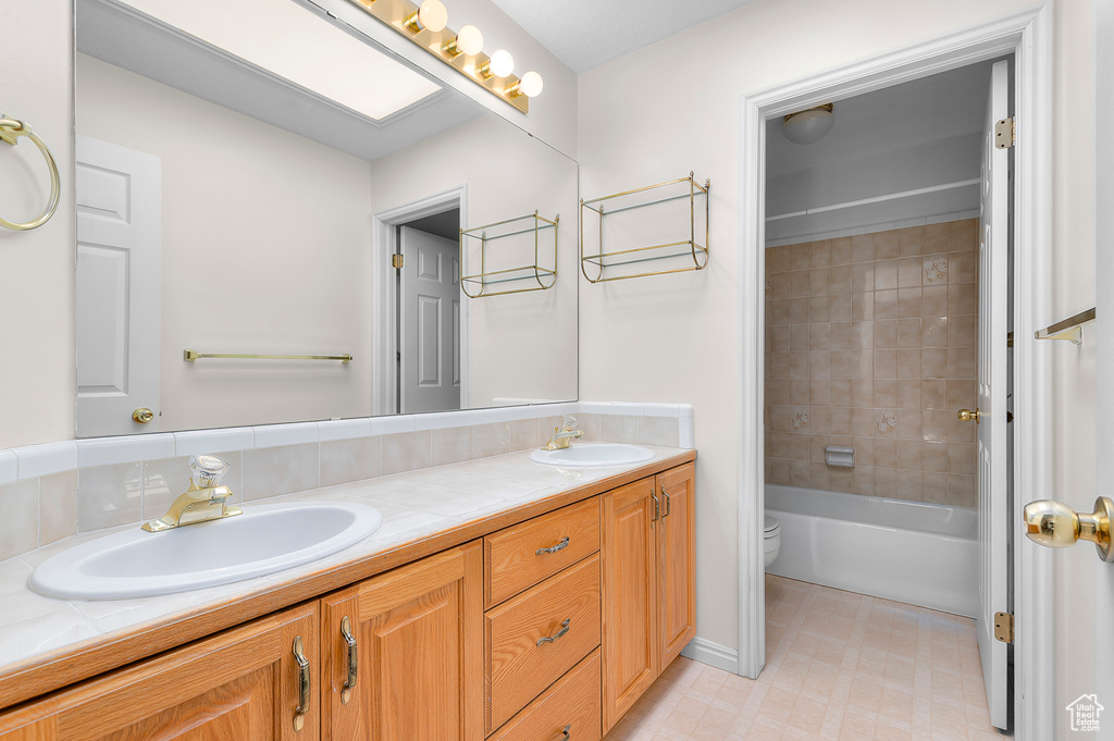 Full bath with double vanity, tile patterned floors, and shower / bathtub combination