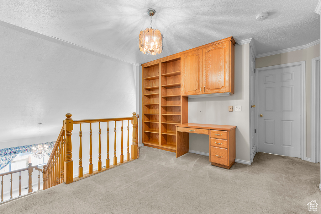 Unfurnished office with a chandelier, light colored carpet, a textured ceiling, and ornamental molding