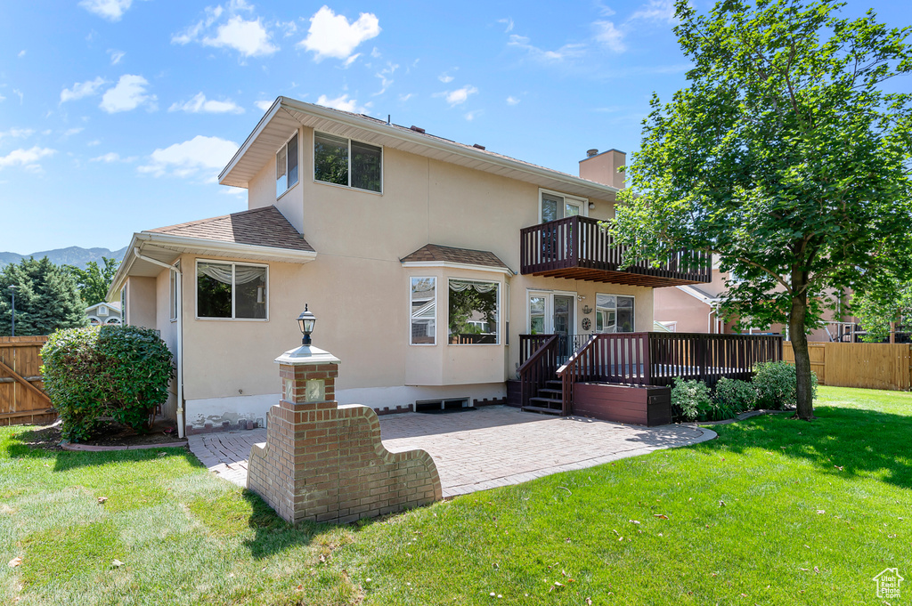 Rear view of property with a balcony, stucco siding, a patio area, a wooden deck, and roof with shingles