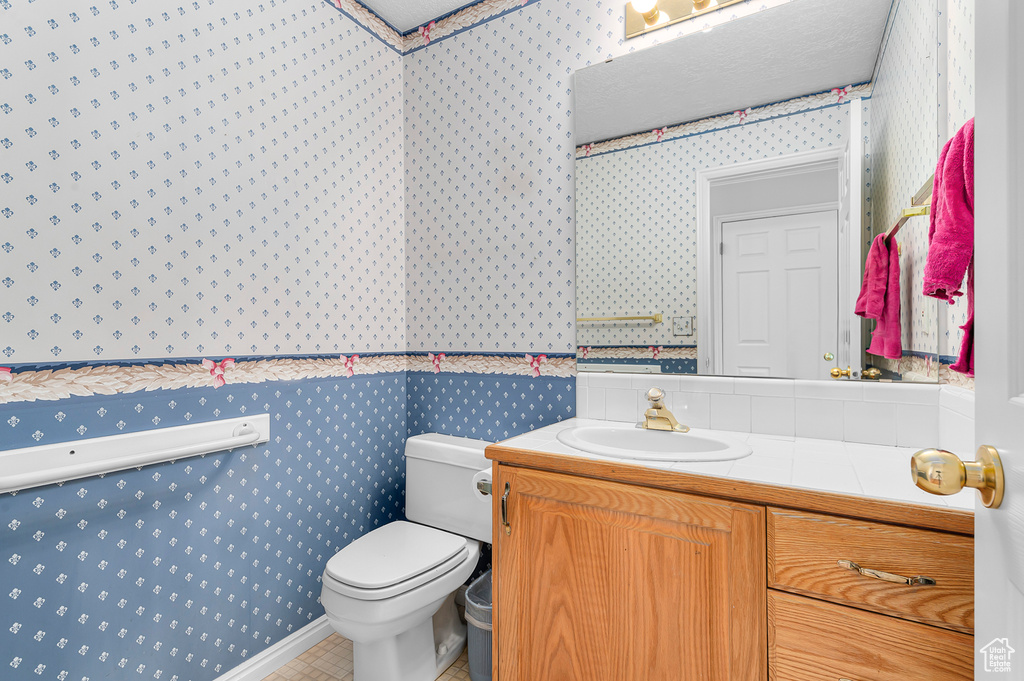 Bathroom featuring wallpapered walls and vanity